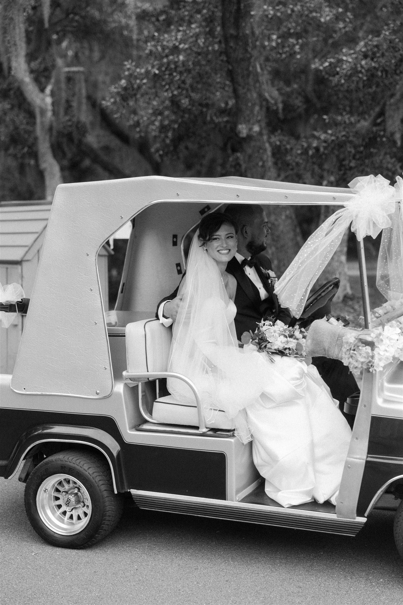 A bride and groom drive in a luxury golf cart decorated for them at one of the Charleston wedding venues