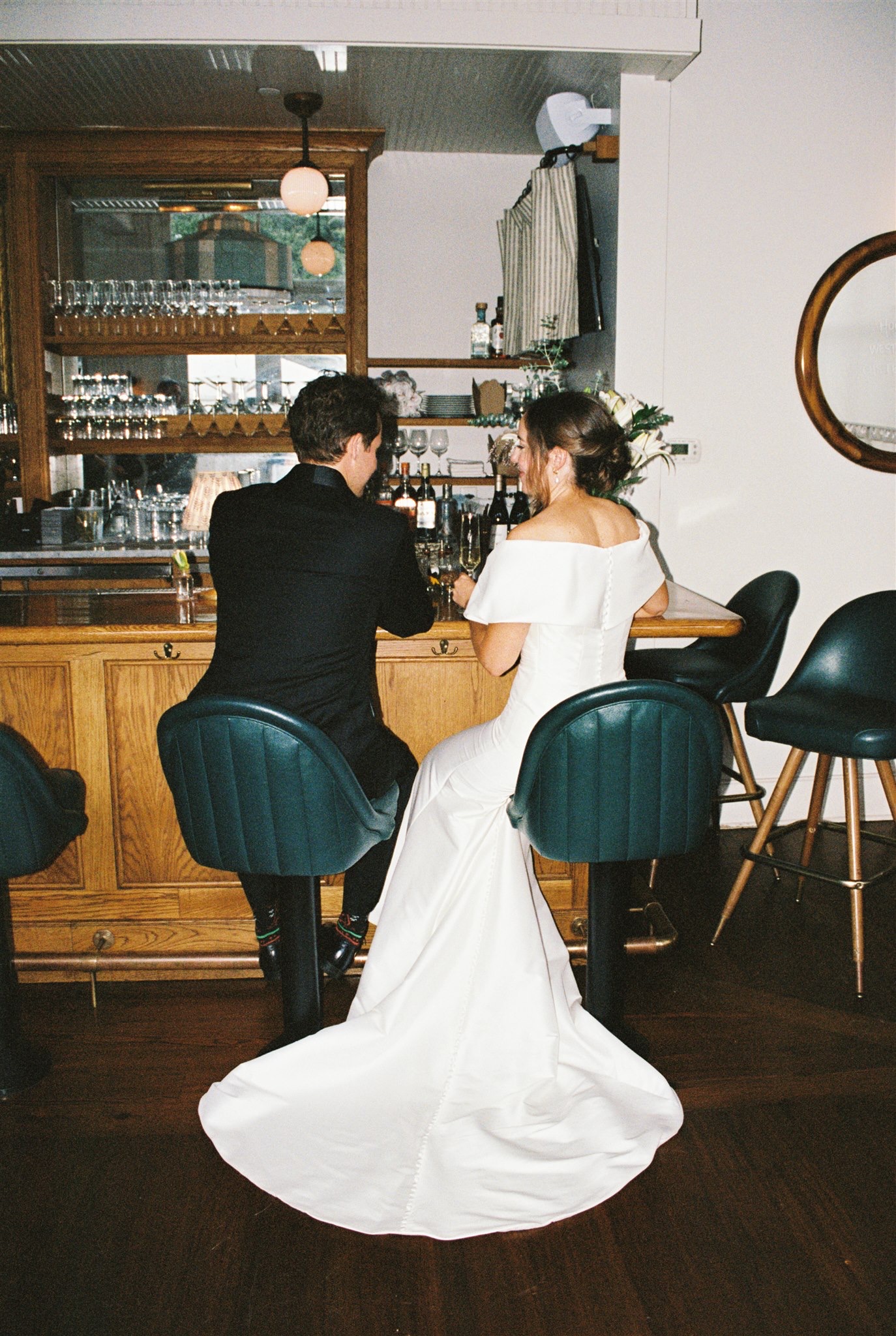 Newlyweds sit at the vintage bar of one of the Charleston wedding venues