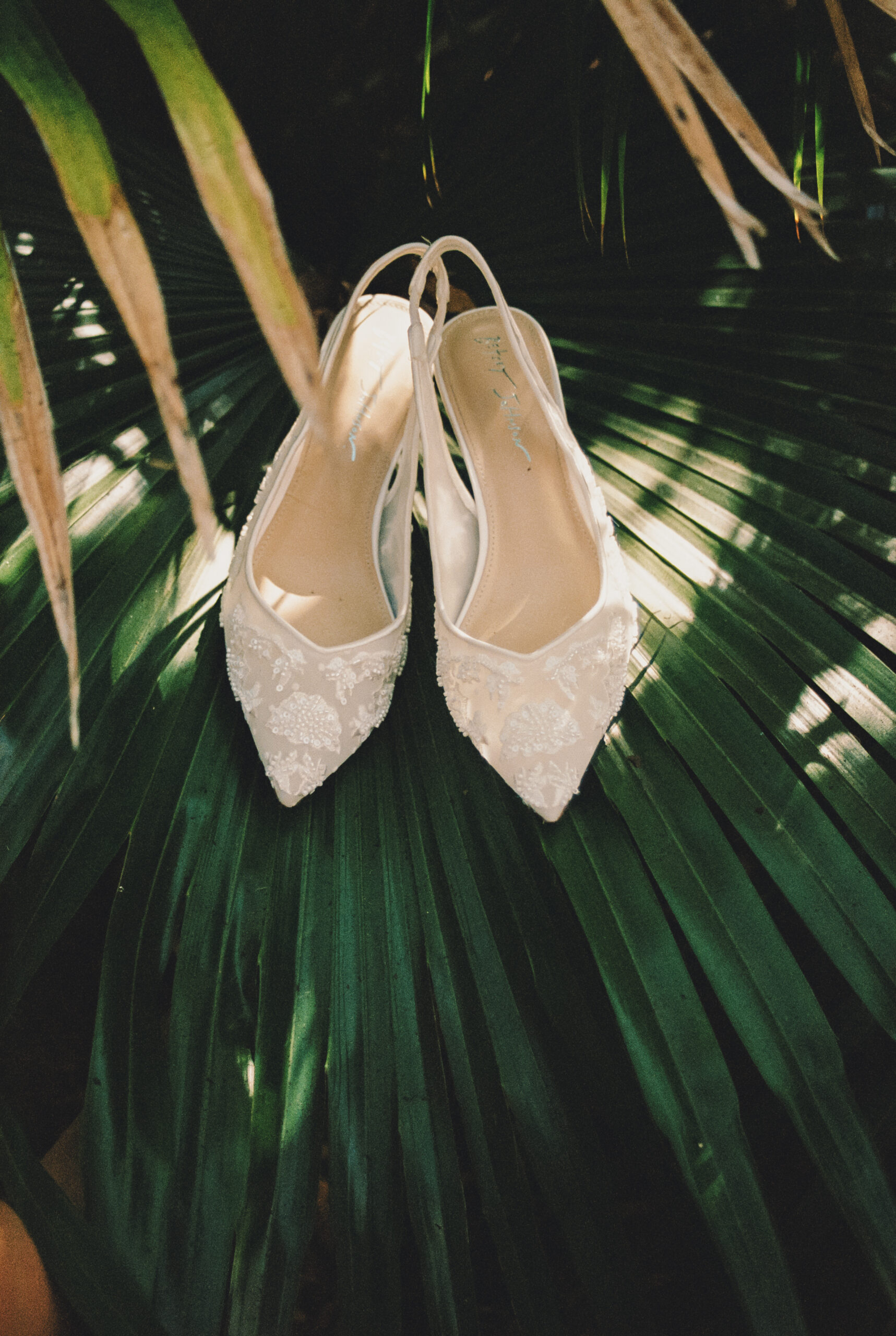 A bride's shoes sit on a saw palmetto branch at one of the Charleston wedding venues