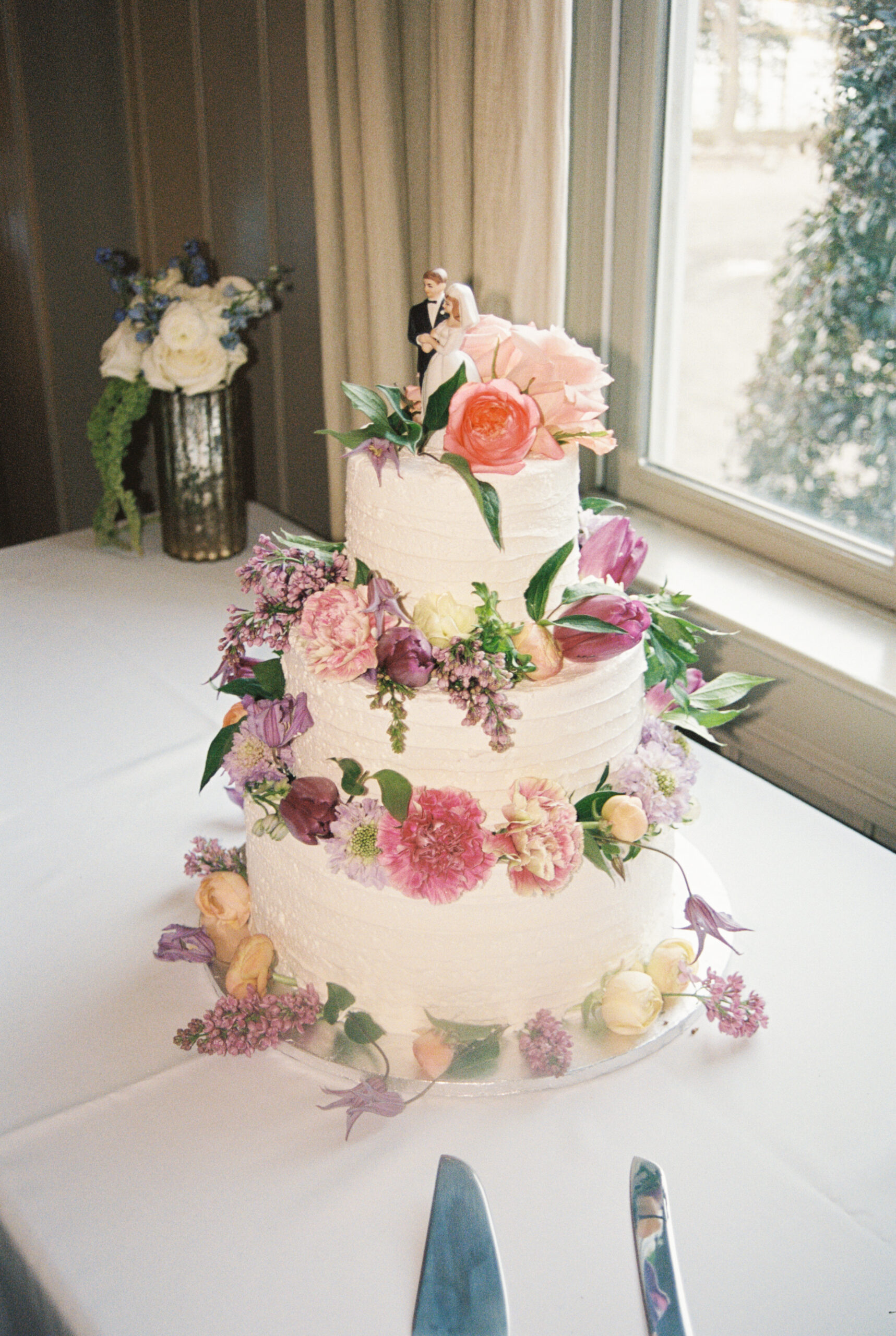 Details of a cake covered in pink and purple flowers