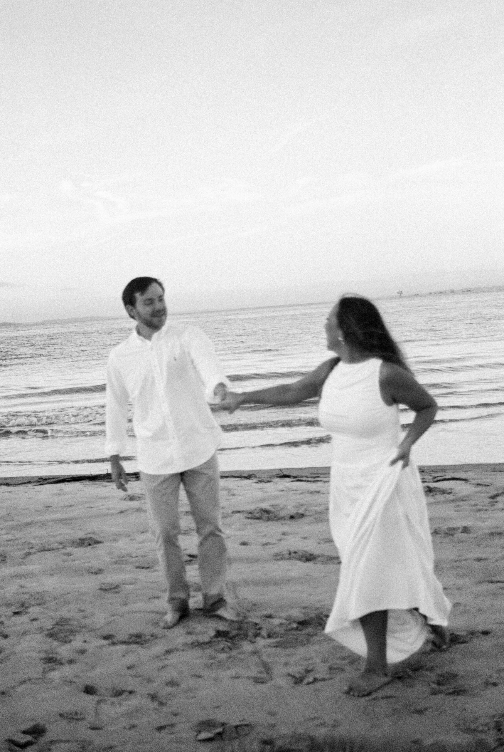 Newlyweds dance on the beach in black and white