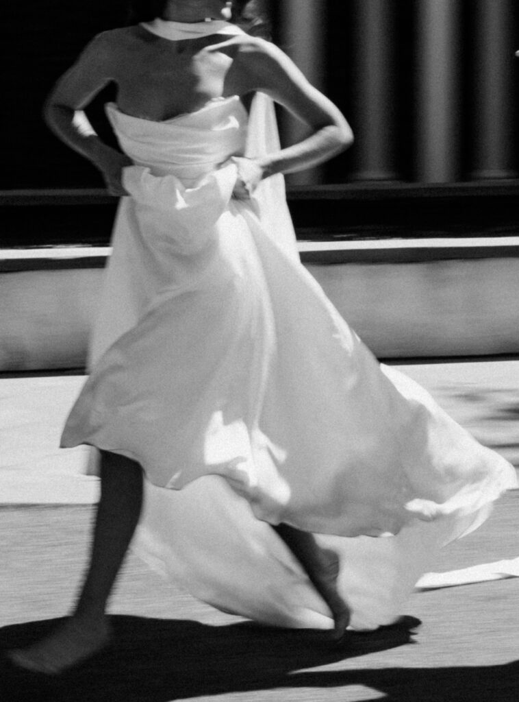A bride holds up her dress while running in the street barefoot