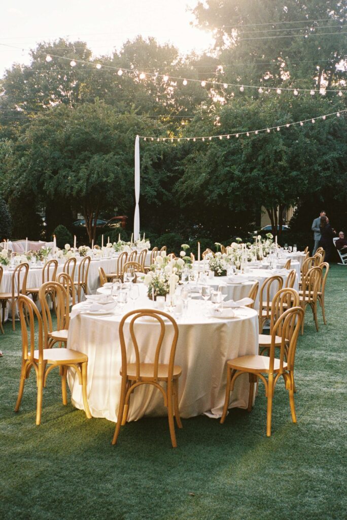 Details of the outdoor reception set up with white linen and wooden chairs for a merrimon wynne house wedding