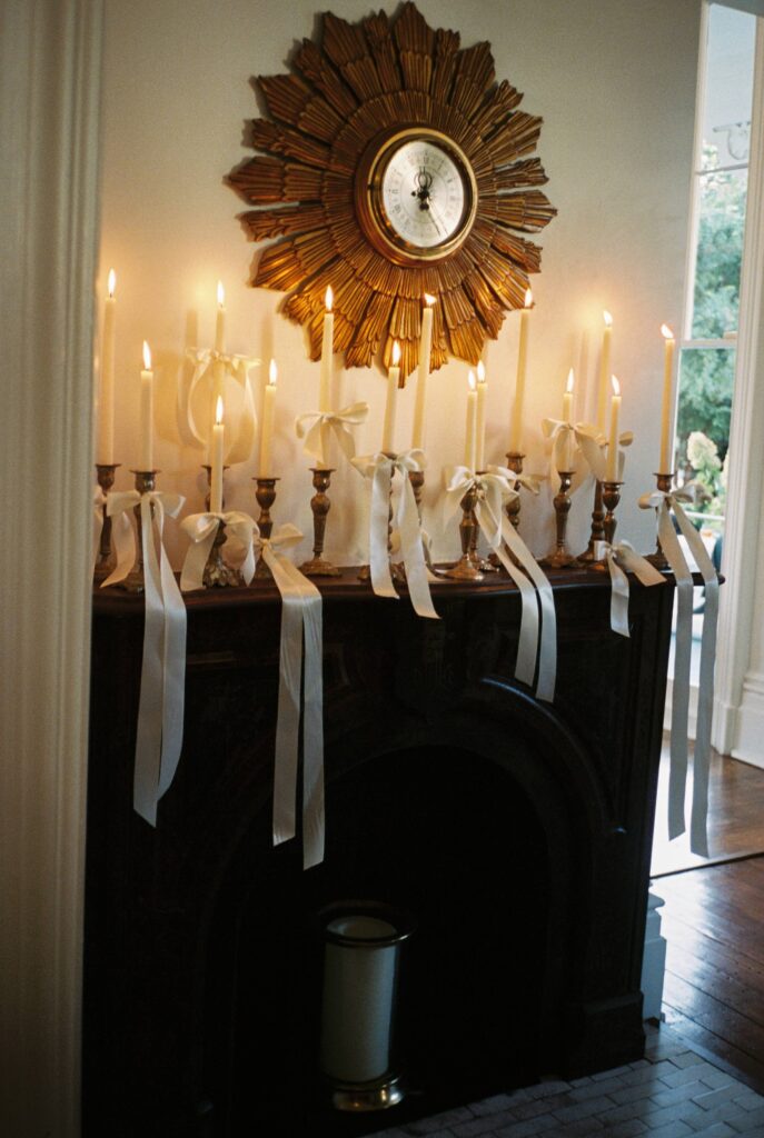 Details of an entry table covered in candles with white ribbons