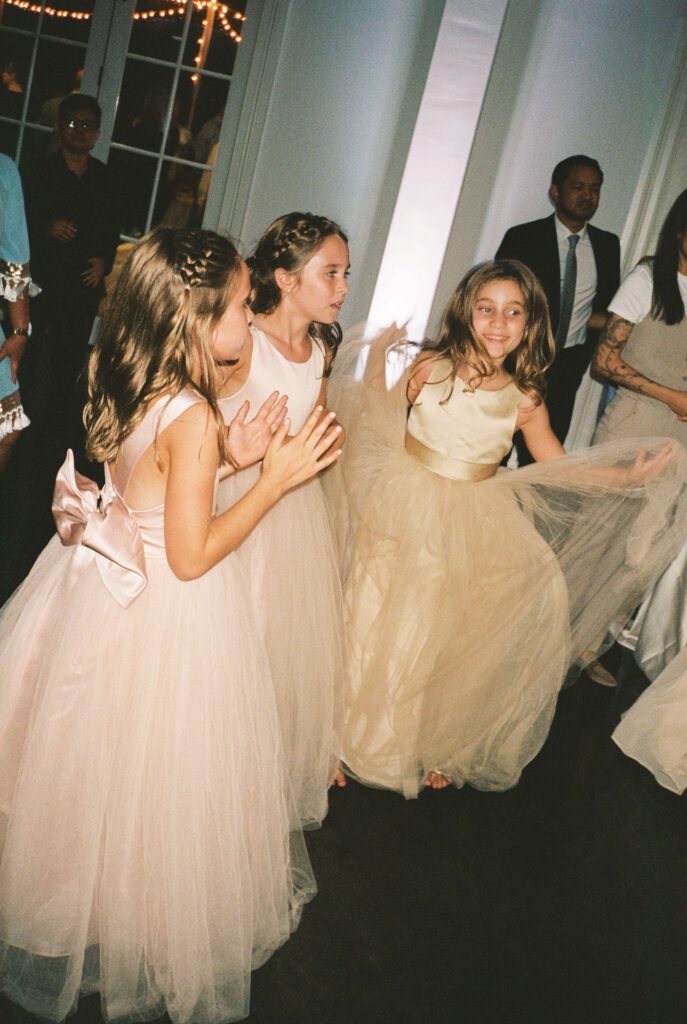 Three young girls in pink dresses dance on the dance floor