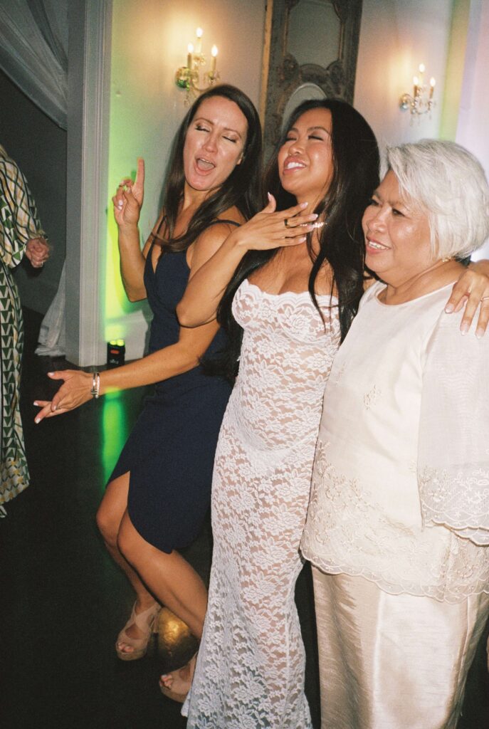 A bride celebrates with a big smile with her mom and a friend