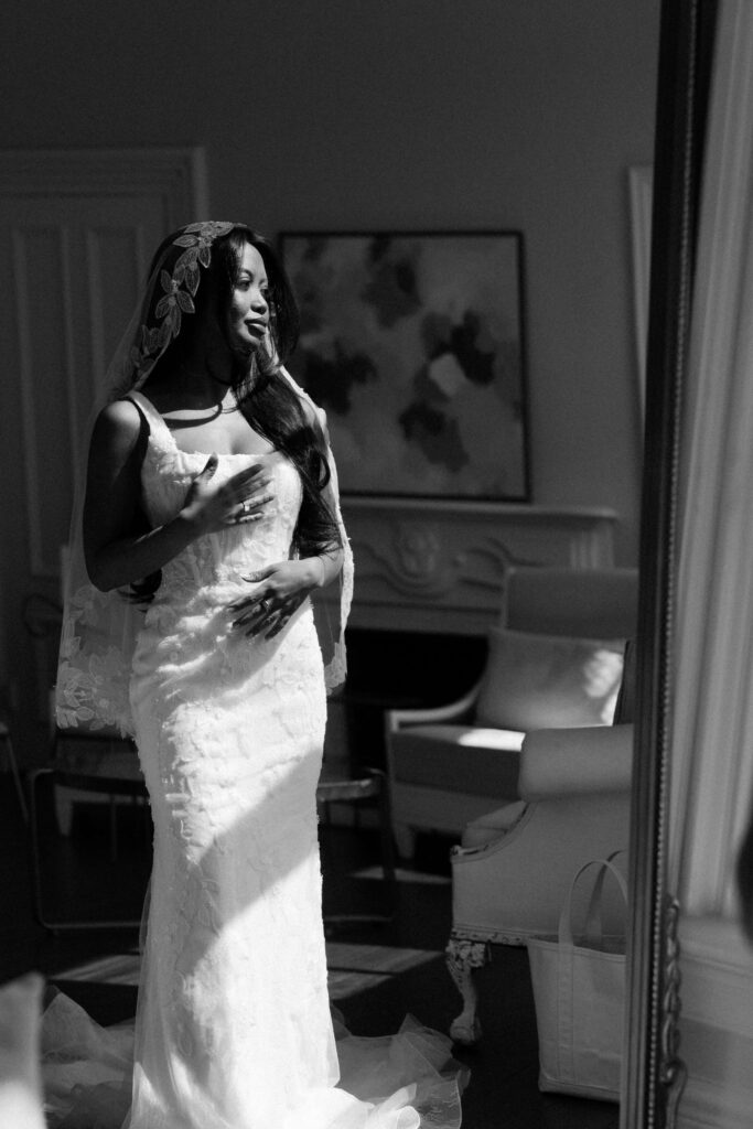 A bride stands in a window in her gown and veil at her merrimon wynne house wedding