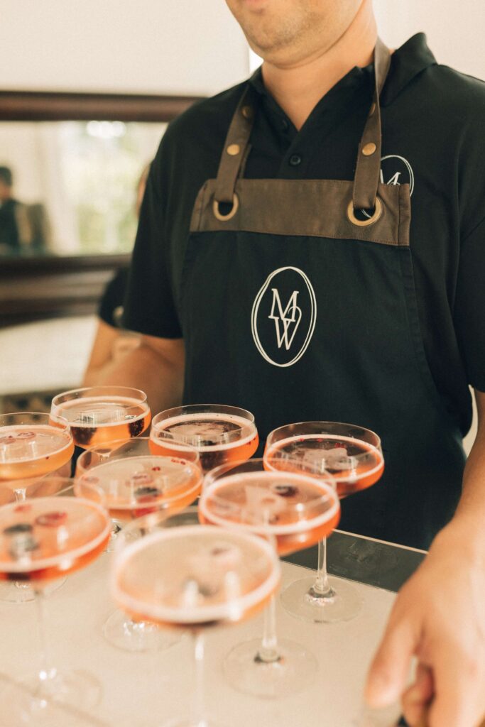 Details of pink drinks on a serving tray held by a waiter at a merrimon wynne house wedding
