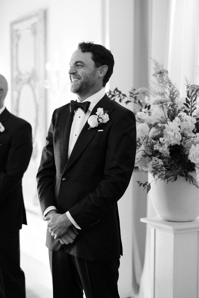 A groom smiles big while watching his bride walk down the aisle