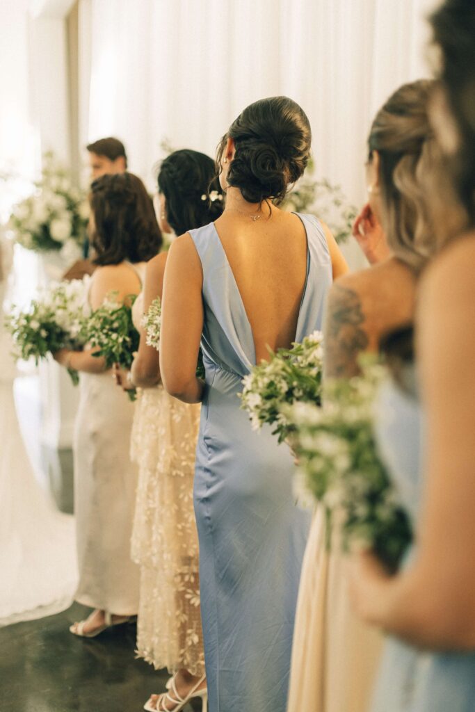 A look down the line of bridesmaids holding their bouquets during a merrimon wynne house wedding ceremony