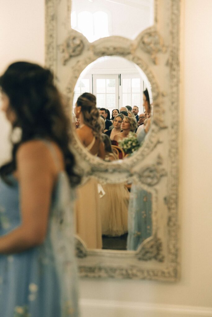 A peek into a mirror at guests during a merrimon wynne house wedding ceremony