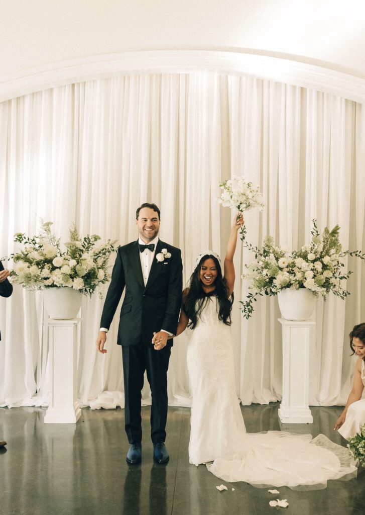 A bride raises her flowers to end her indoor ceremony with her groom at their merrimon wynne house wedding