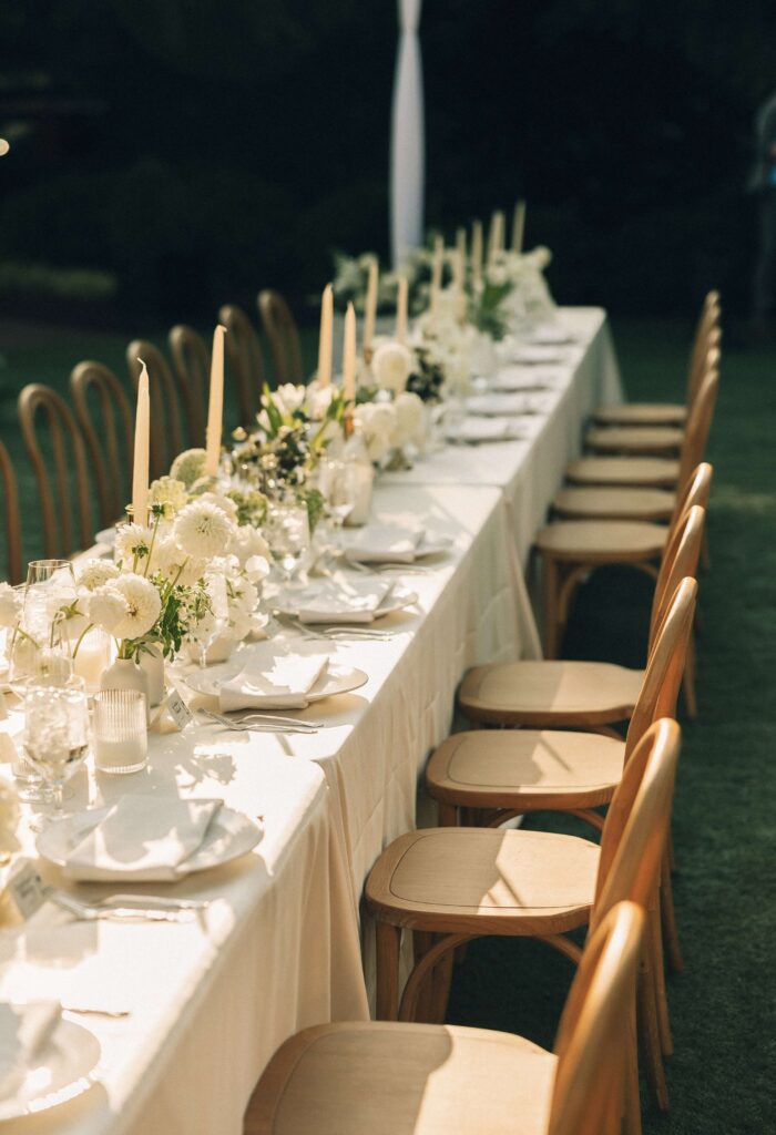 A look down a long merrimon wynne house wedding reception table with white carnations and candles
