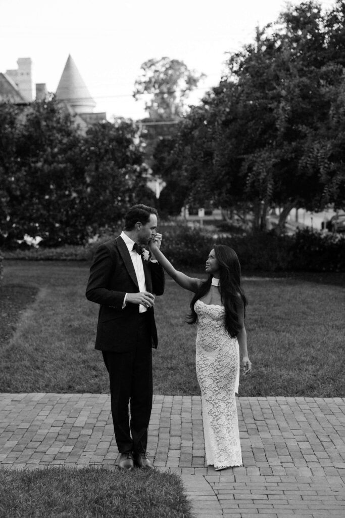 A groom kisses the hand of his bride in the front patio of the merrimon wynne house wedding venue