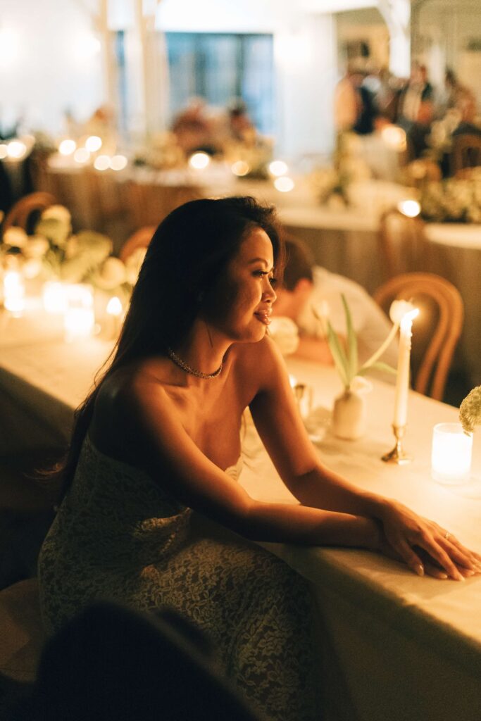 A bride sits at a reception table at her merrimon wynne house wedding