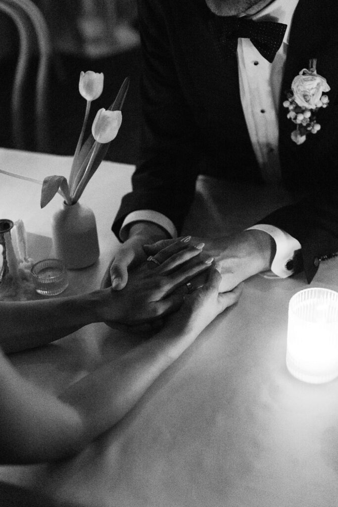Details of newlyweds holding hands on a table in black and white