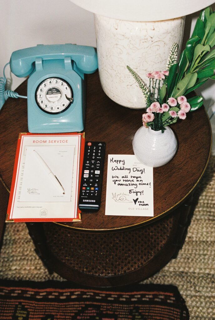 Details of a side table with a vintage phone and lamp and note from the wedding venue team to the bride