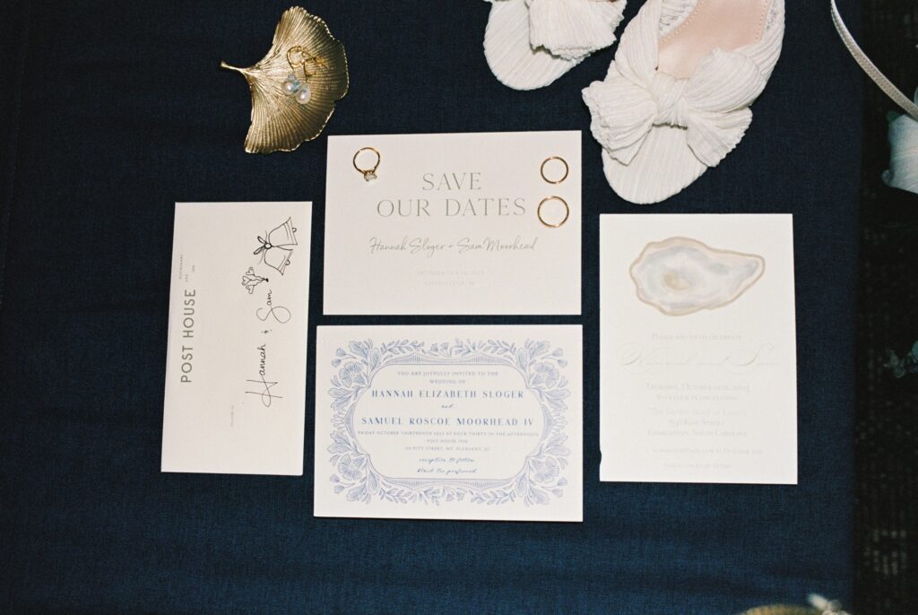 Bridal details with rings and invitations on a blue table with pearl earrings and shoes