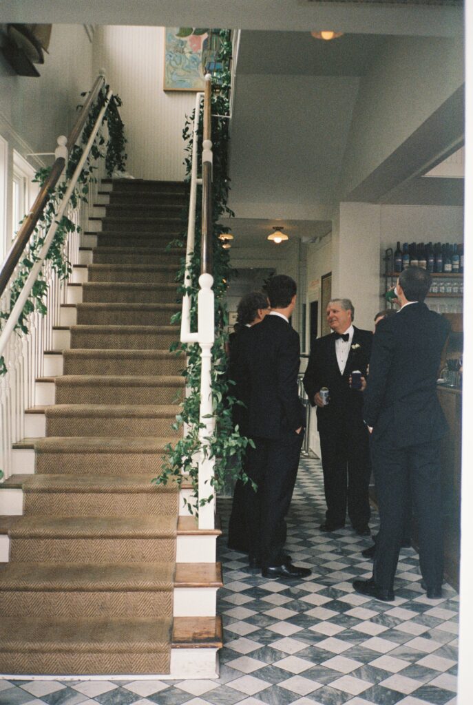A look at the main stairs as guests chat at the bar during a Post House Inn wedding