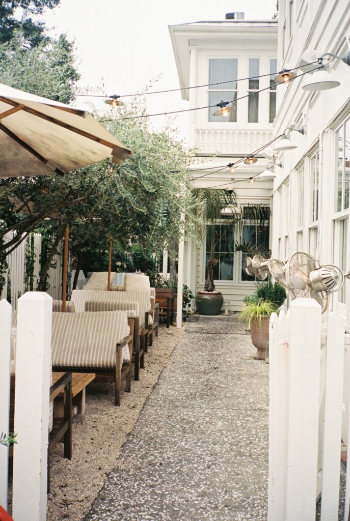 A look down the side patio with market lights and umbrellas behing white picket fence