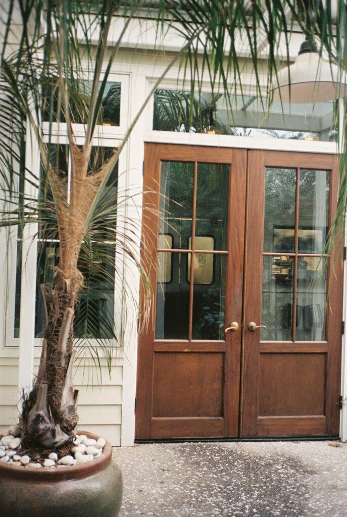 Details of the vintage wooden doors framed by a palm tree at the Post House Inn wedding venue
