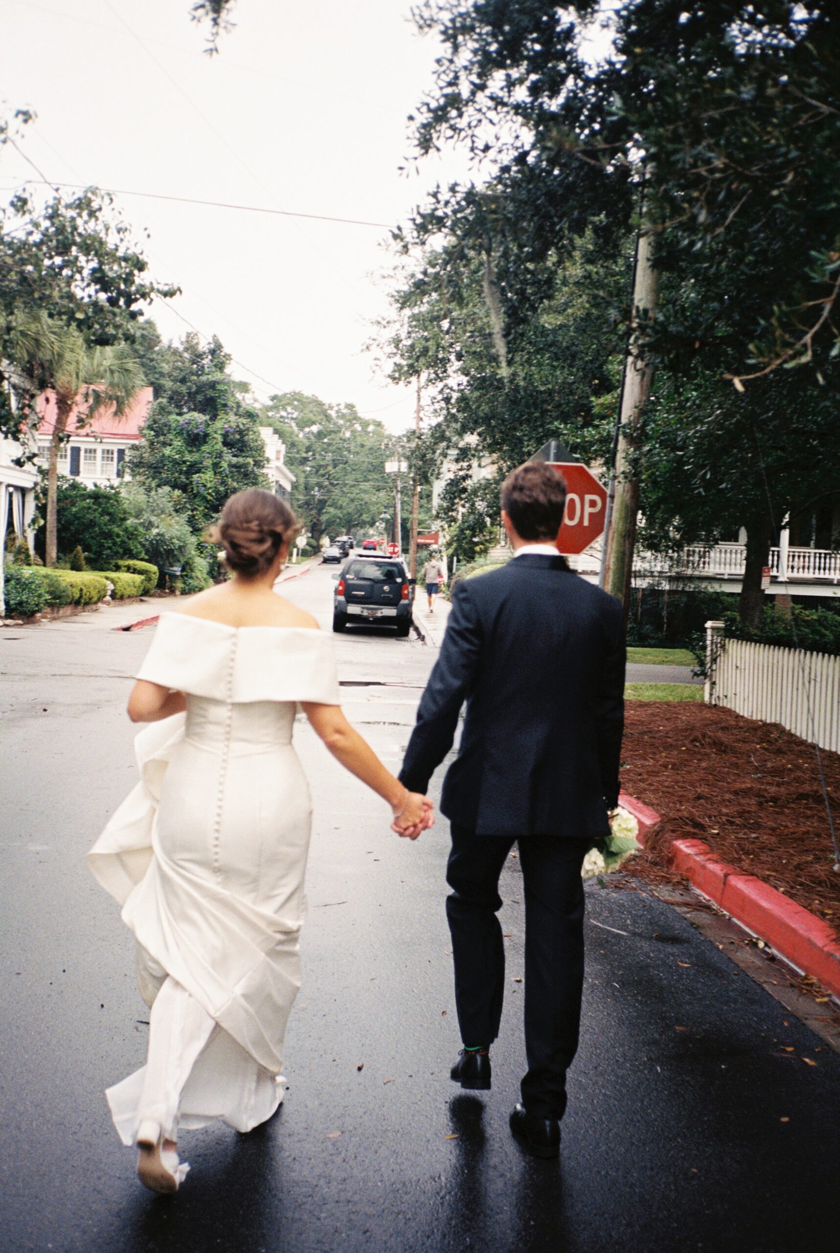 Newlyweds walk down the wed street holding hands during their Post House Inn wedding