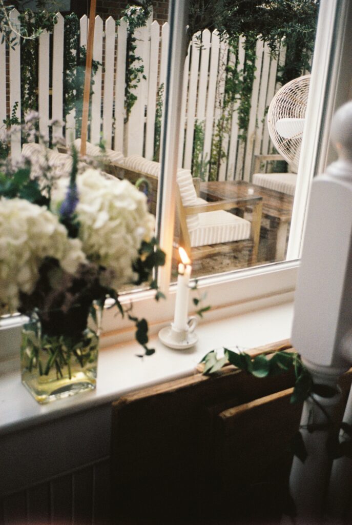 Details of a candle burning on a windowsill overlooking the garden patio