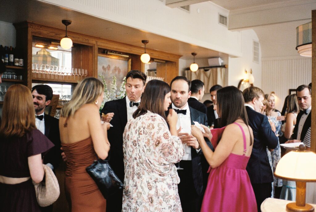 Wedding guests chat and enjoy cocktail hour at the vintage bar of the Post House Inn wedding venue