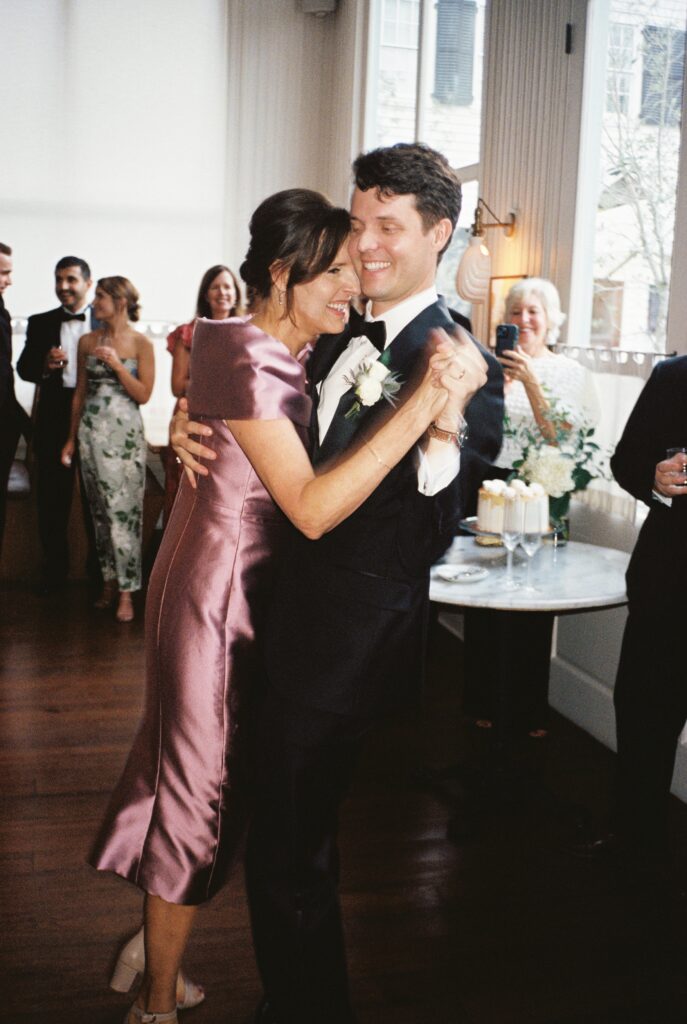 A groom laughs with his mom as they dance during the wedding reception