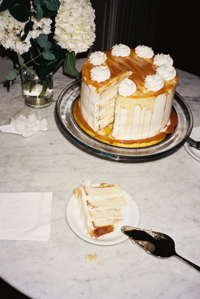 Details of a caramel covered cake with a single slice on the marble table