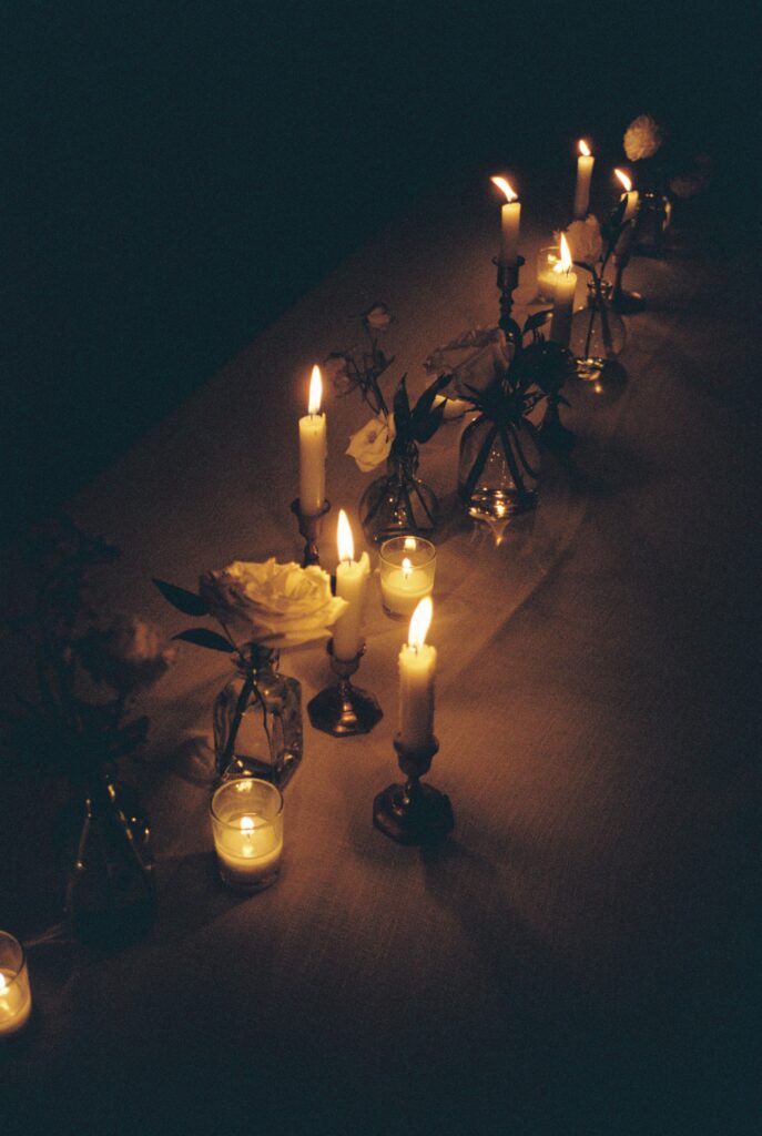Details of a candle lite table setting on white linen with white roses at a Post House Inn wedding reception