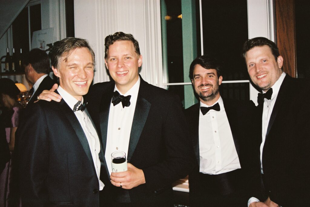 A groom laughs and smiles with his groomsmen during his reception