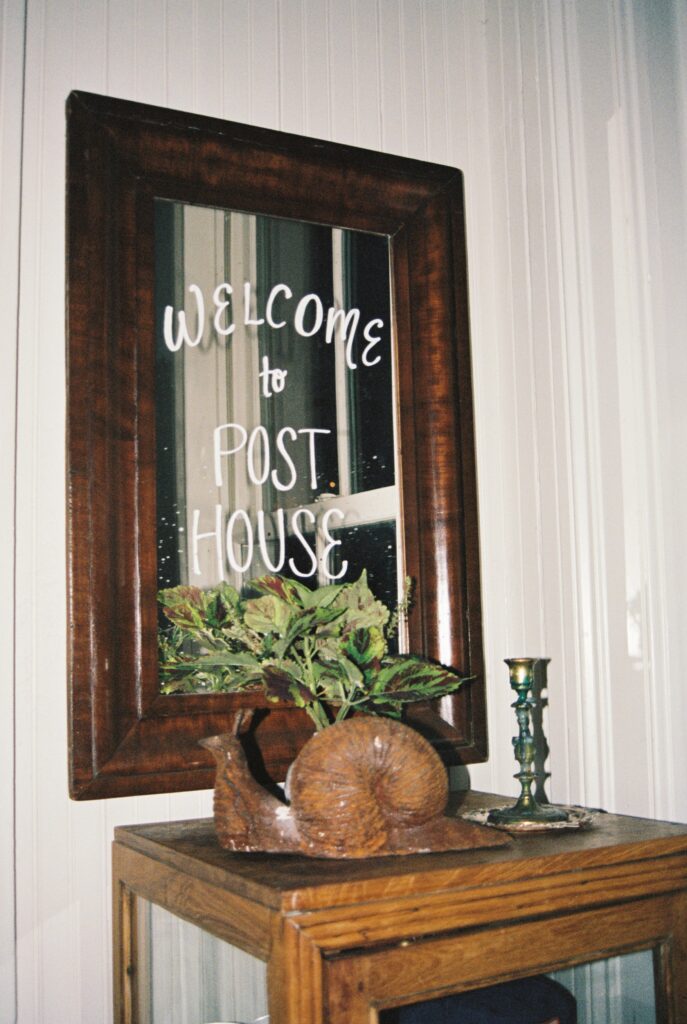 Details of a Post House Inn wedding venue welcome sign painted on a mirror above a table