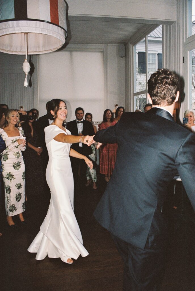 A bride smiles big while dancing with her husband for the first time at their Post House Inn wedding
