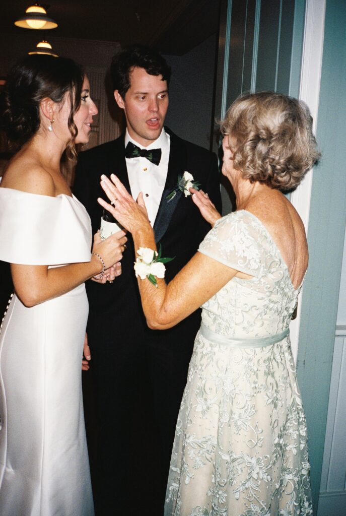 Newlyweds chat with a woman in a blue dress during their reception