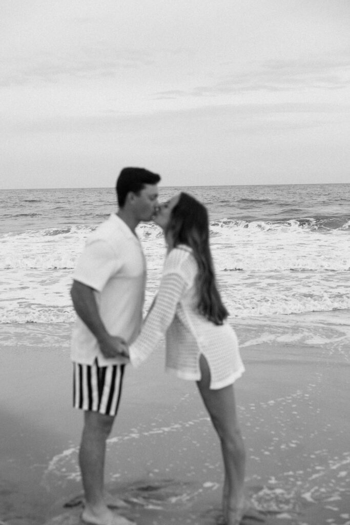 NEwlyweds in bathing suits kiss and hold hands on the beach in the water