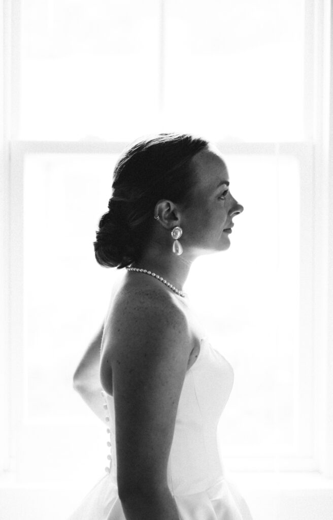 A profile in black and white of a bride standing in a window at one of the Wilmington wedding venues
