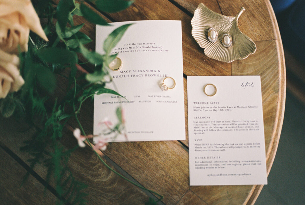 Details of a bride's jewelry and invitations on a wood table