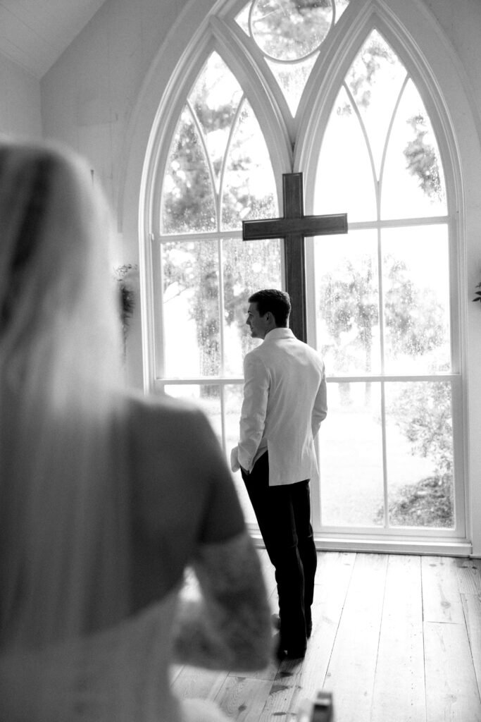 A groom waits at the altar in his white tux jacket