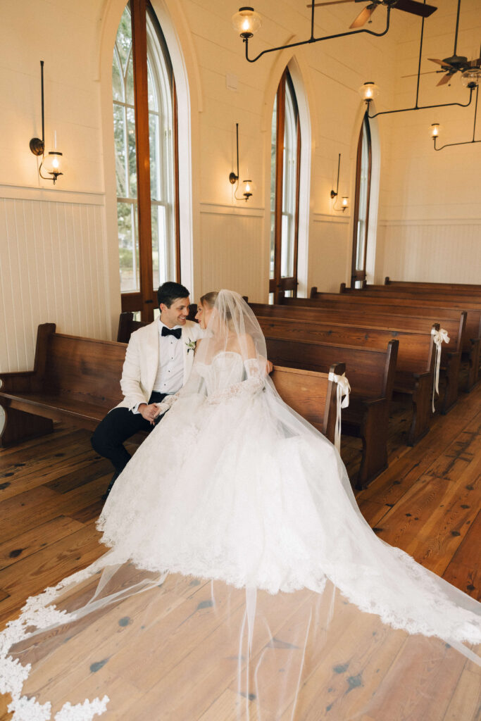 Newlyweds cuddle and hold hands in the front chapel pew of the montage palmetto bluff wedding ceremony space