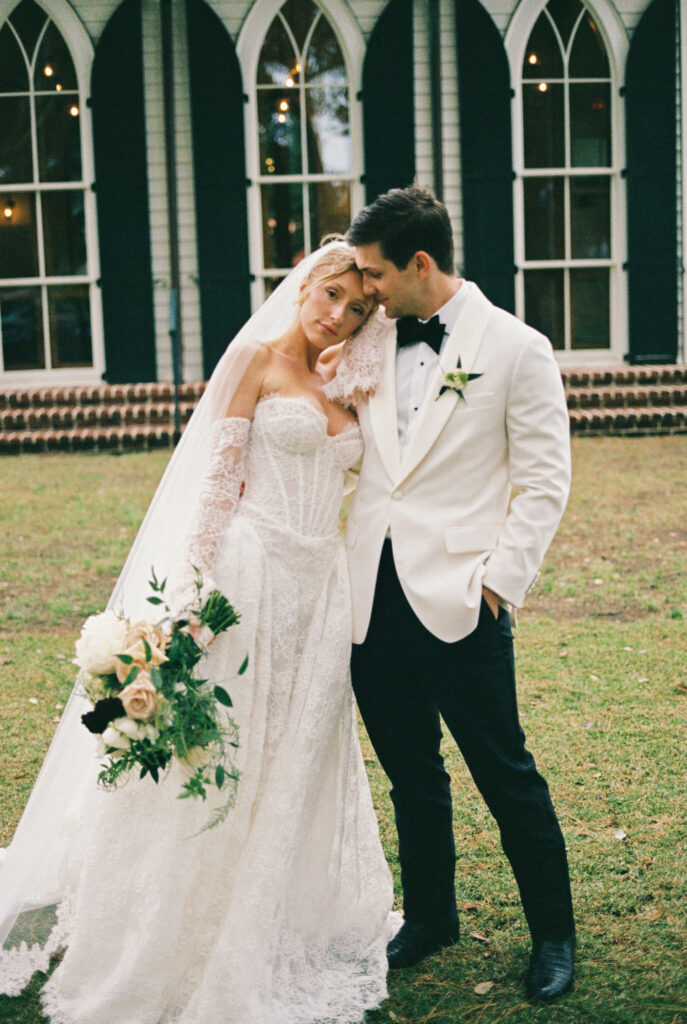 A bride snuggles on her groom's shoulder as they stand in a lawn after their montage palmetto bluff wedding ceremony