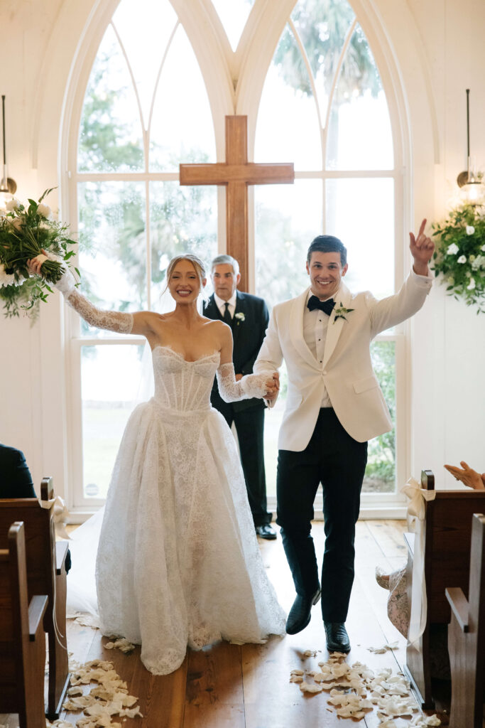 Newlyweds celebrate with hands up while walking up the montage palmetto bluff wedding chapel aisle ending their ceremony