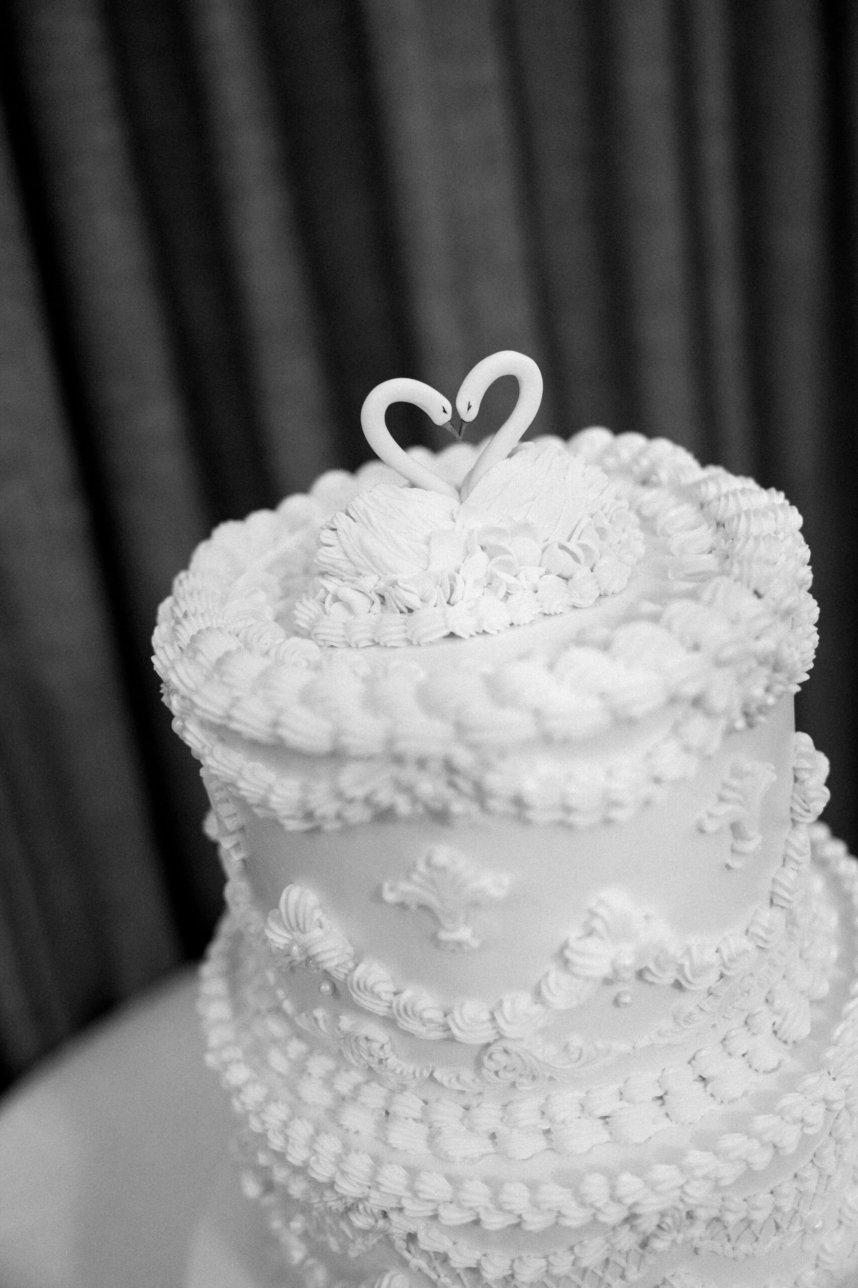 Details of a three tier wedding cake with swans on top