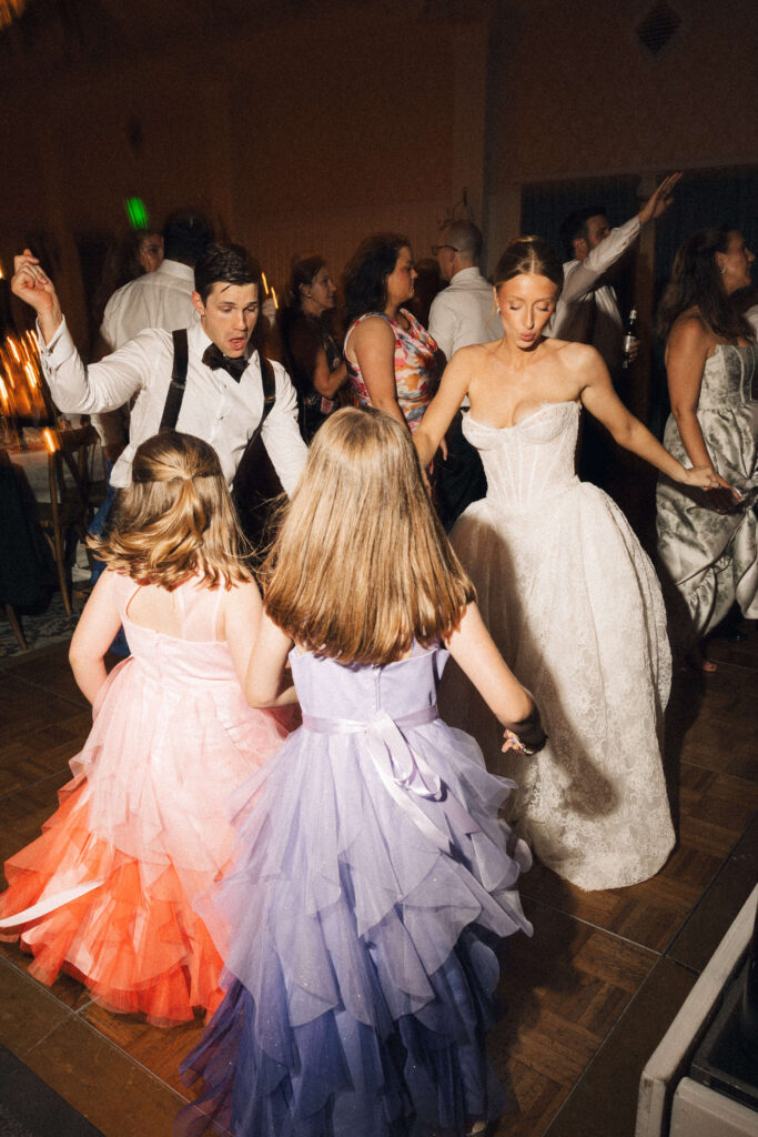 Newlyweds dance with two young girls in matching tule gown of purple and pink during a montage palmetto bluff wedding reception
