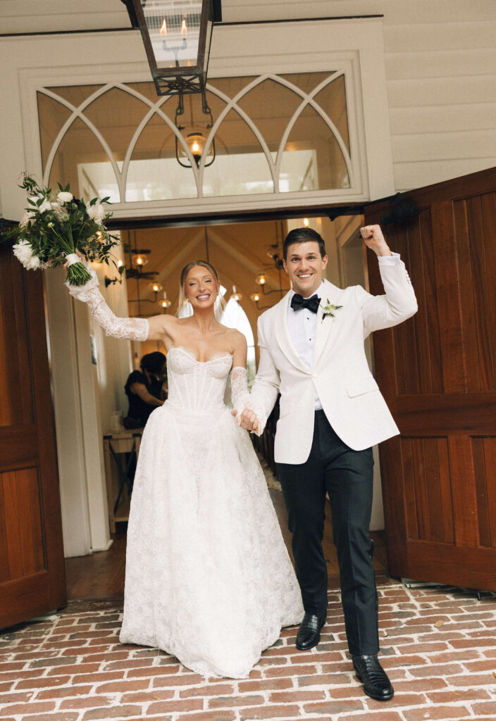 Newlyweds raise their hands in joy while exiting their ceremony