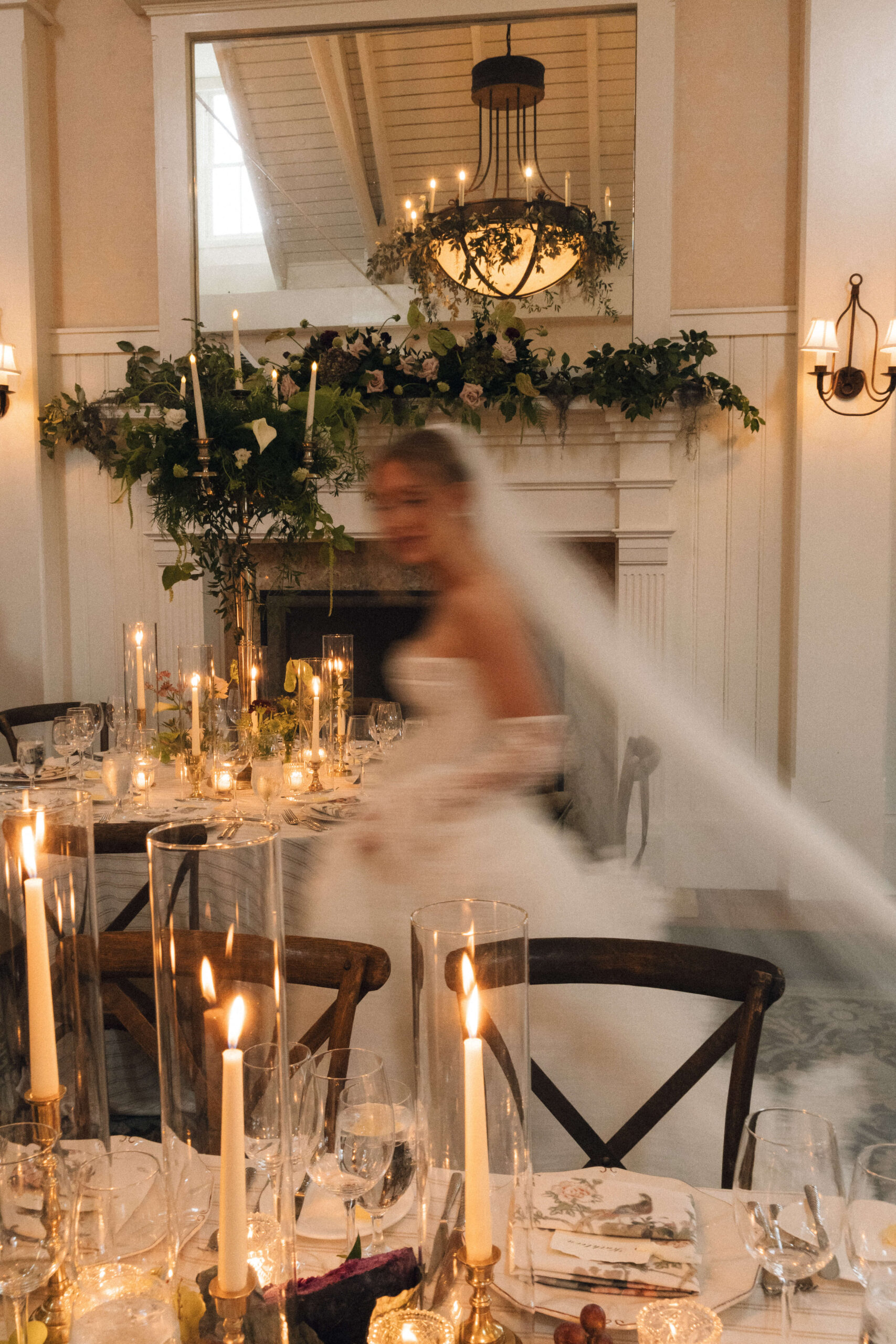 A bride in motion moving through a set up reception hall with candles
