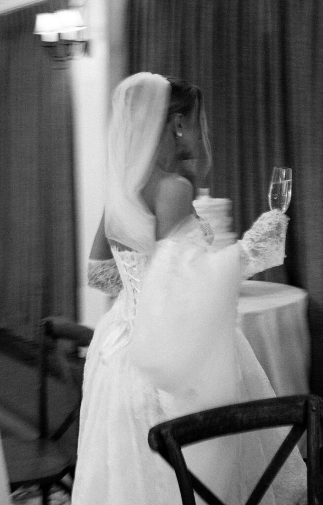 A bride walks through her reception space with a glass of champagne